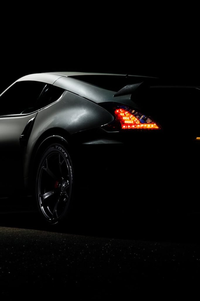 A dramatic shot of a Nissan 370Z sports car illuminated in darkness with vibrant tail lights.